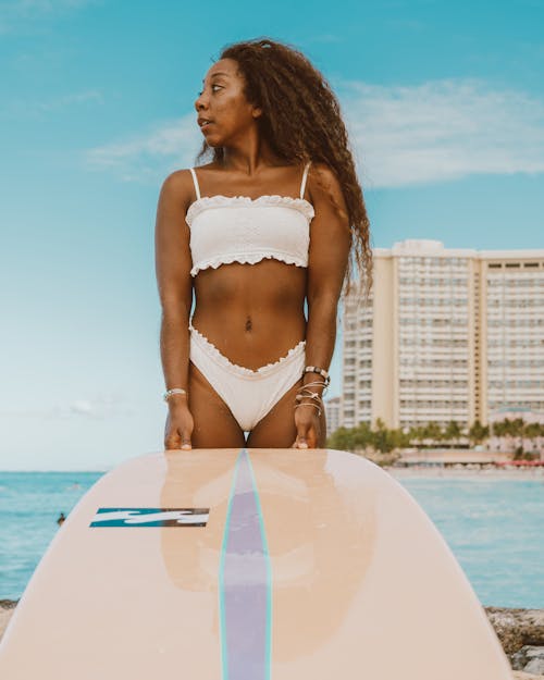 Close-up Shot A Woman in a Bikini Standing While Holding Her Surfboard
