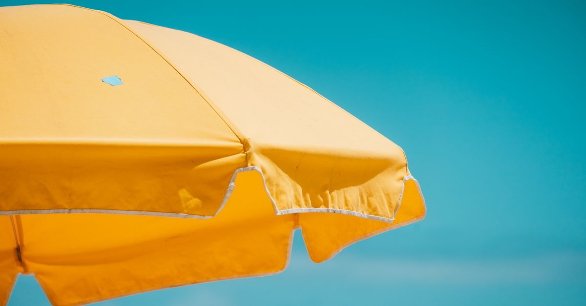 A vivid yellow beach umbrella set against a clear blue sky, capturing the essence of summer.