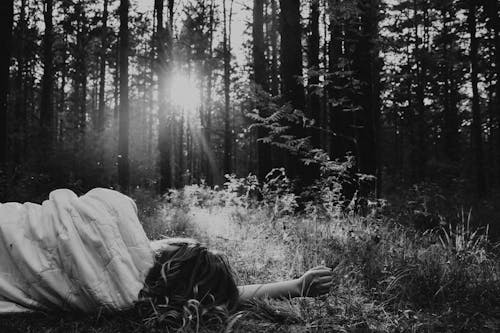 A Grayscale Photo of a Person Lying on the Grass