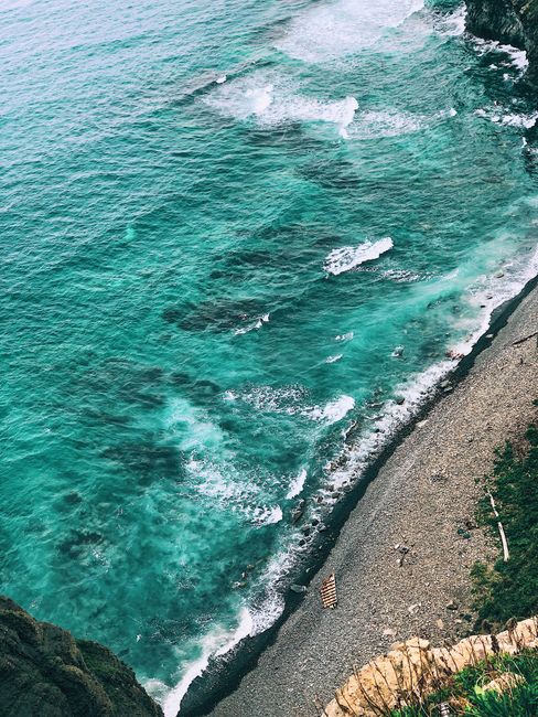 Stunning aerial shot of turquoise ocean waves crashing on a rocky Russian coastline.