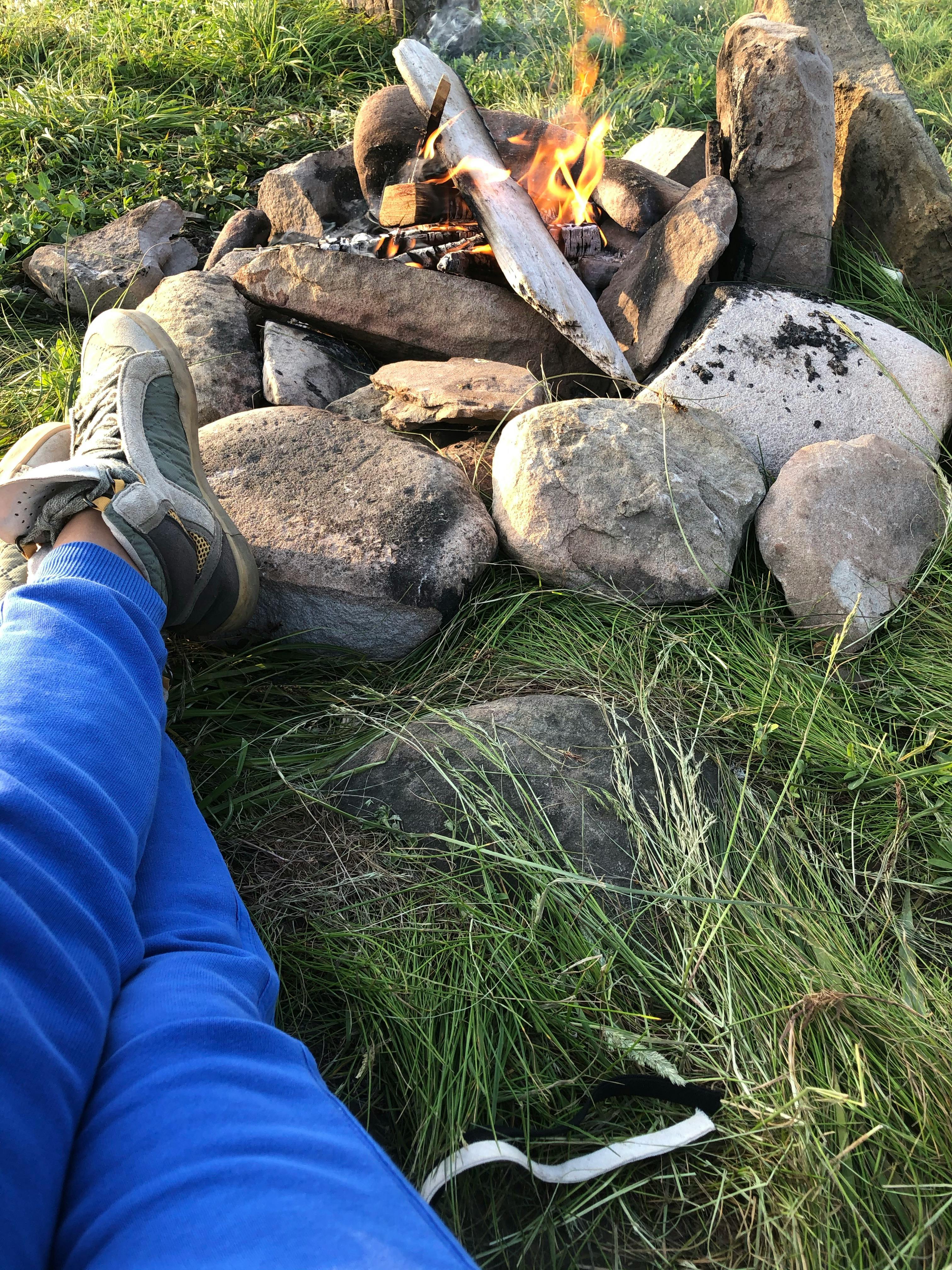 photo of a person lying near a campfire with rocks