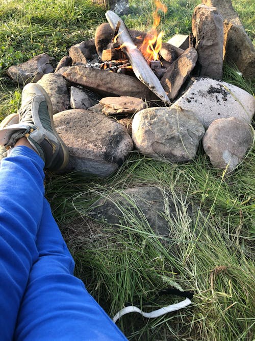 Photo of a Person Lying Near a Campfire with Rocks