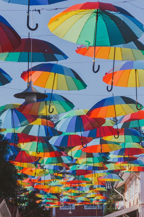 Free A stunning display of colorful umbrellas suspended above the street in Penedo, Brazil. Stock Photo