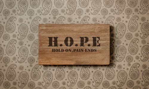 Free Rustic wooden sign with motivational 'H.O.P.E' message on patterned wallpaper. Stock Photo