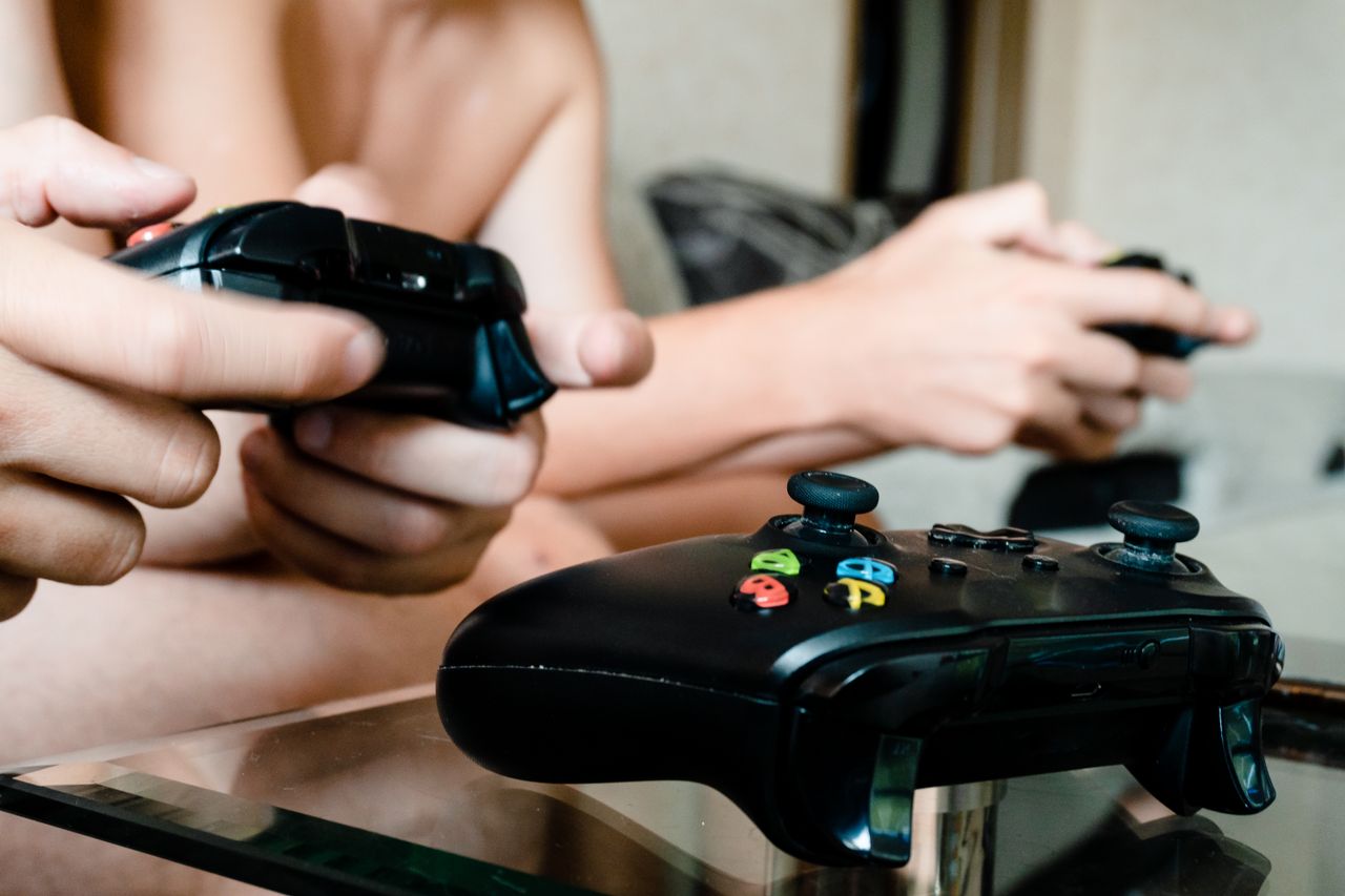 two people playing video games with controllers on a glass table indoo
