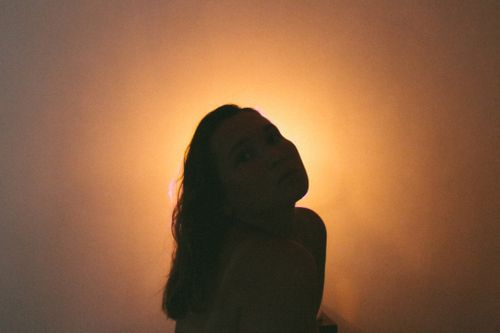 Free Artistic silhouette of a woman backlit by warm yellow light, creating a dramatic mood. Stock Photo