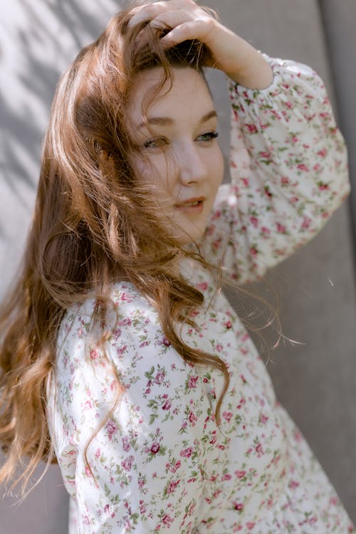 A Woman in Floral Long Sleeves with Her Hand on Her Hair