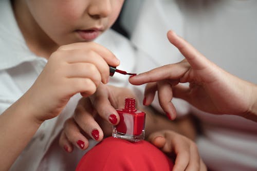 Free Photograph of a Kid Painting a Person's Fingernails Stock Photo