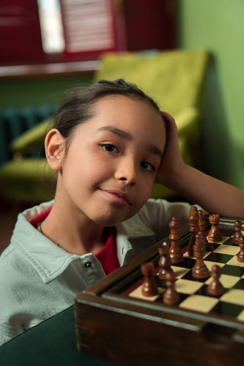 Free A Girl with Her Hand on Her Head Near the Chessboard Stock Photo