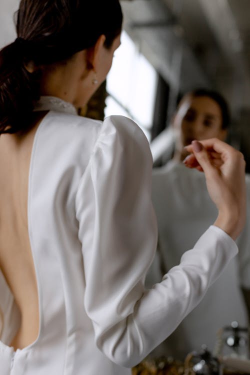 A Woman in White Long Sleeves Looking at the Mirror