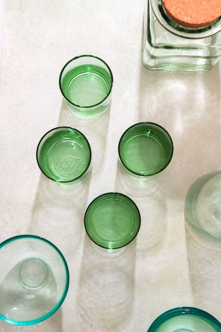 Minimalist flat lay of green glassware on a light surface with natural light.