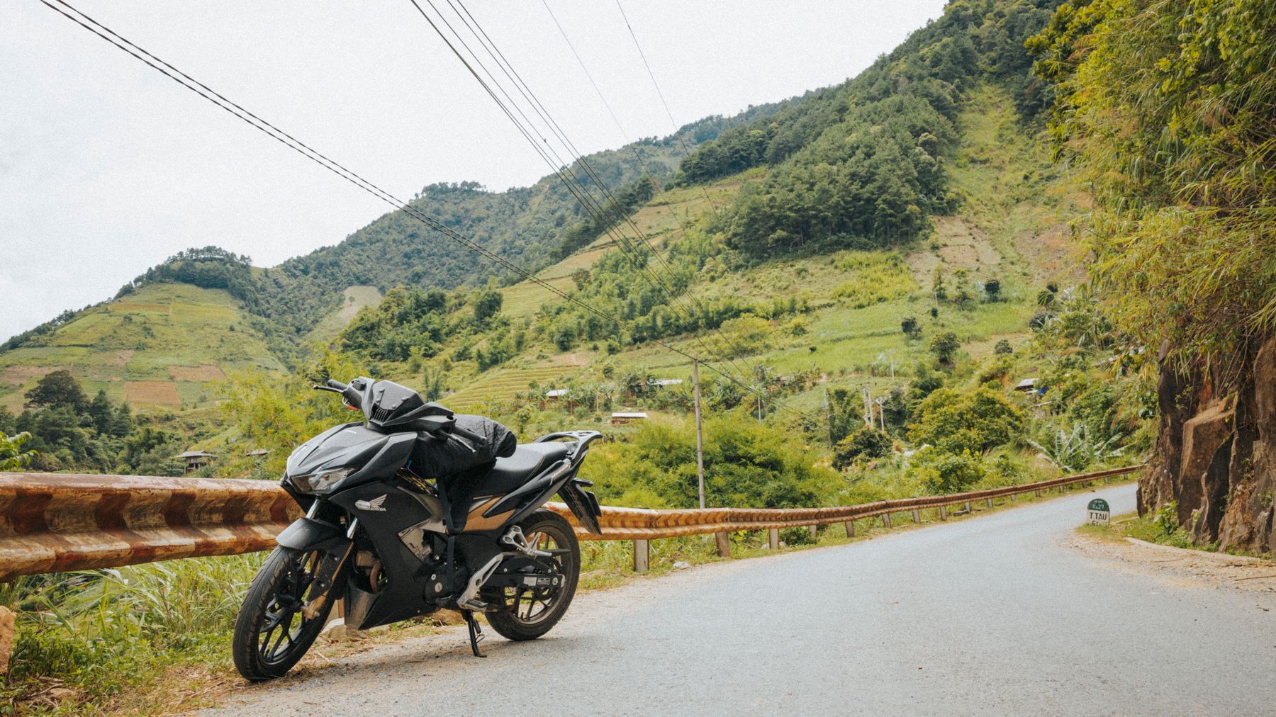 A sleek motorcycle parked on a scenic mountain road with lush greenery and hills.