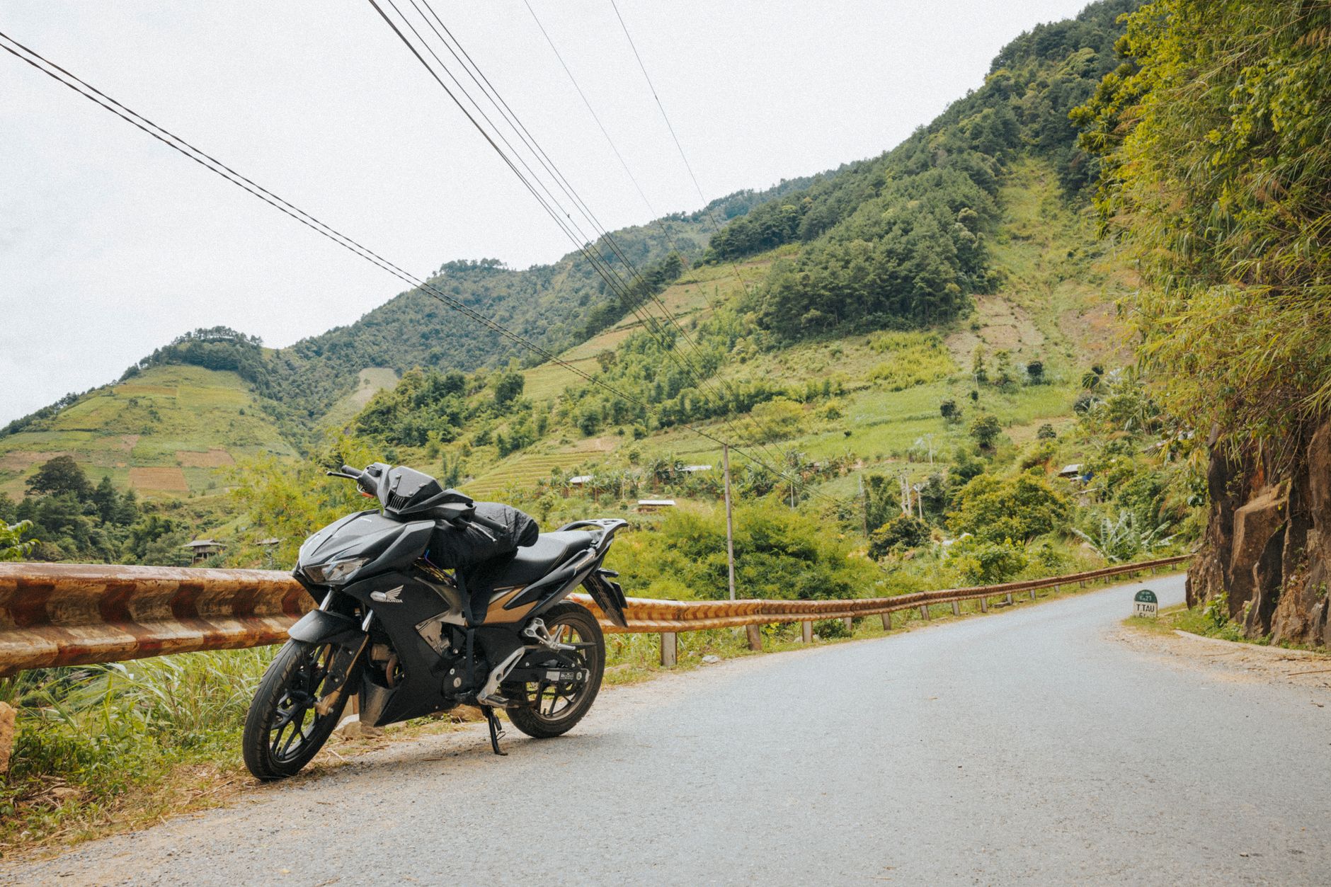 A sleek motorcycle parked on a scenic mountain road with lush greenery and hills.