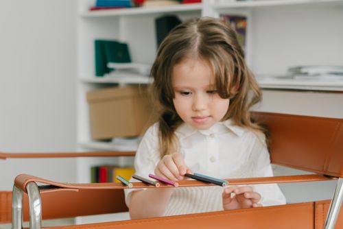 Free A young caucasian girl arranging colored pencils indoors, focusing intently. Stock Photo