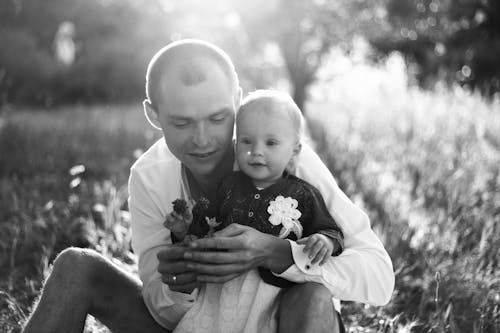 Grayscale Photo of a Man Carrying a Kid