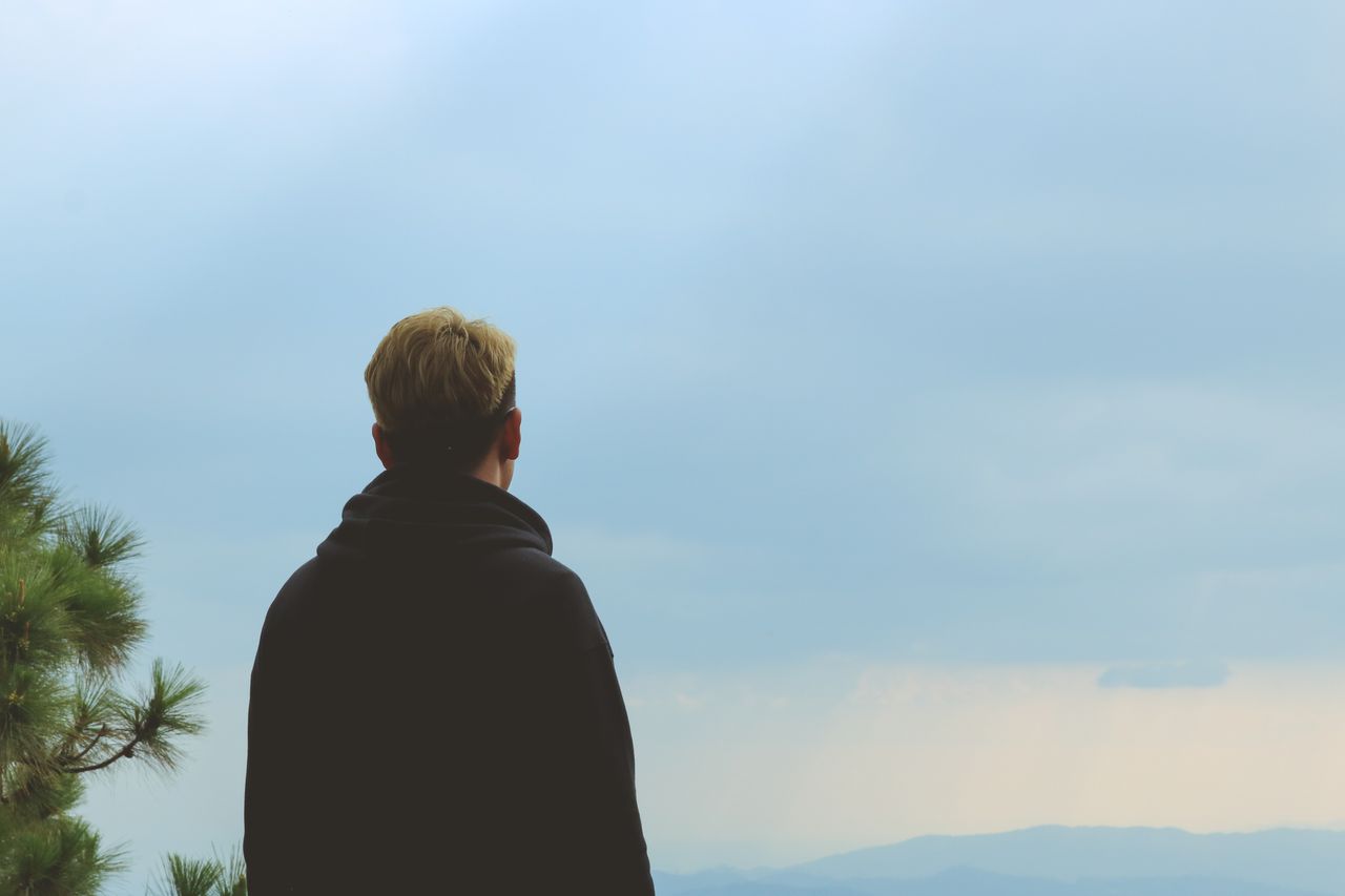 a lone person standing outdoors looking at a cloudy sky embodying soli