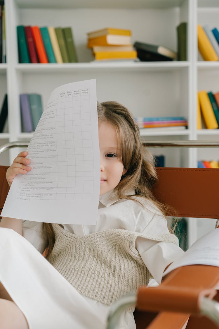 Photograph Of A Child Holding A White Piece Of Paper