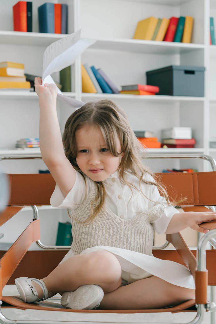 Girl In White Dress Raising Her Hand While Holding A Paper 