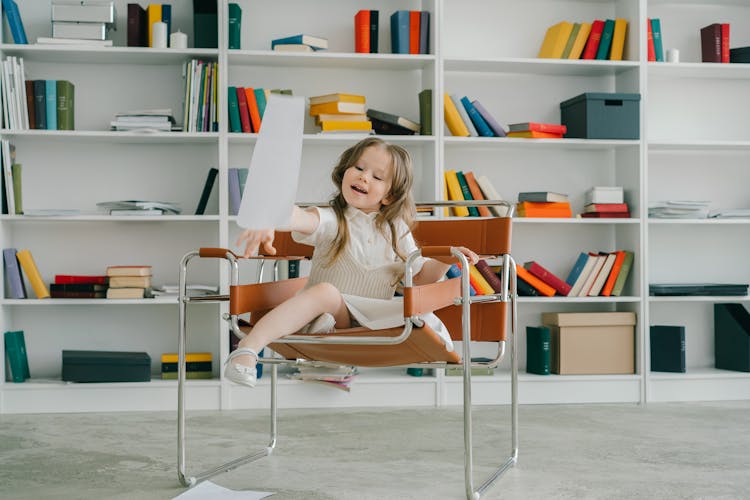 Girl Sitting On A Chair Throwing Paper 