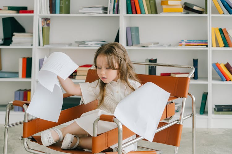 Photograph Of A Kid Holding Sheets Of Paper