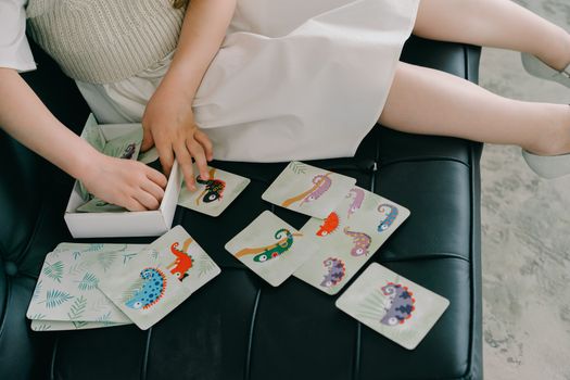 A child sitting on a couch playing with colorful educational animal cards indoors promoting learning and fun.