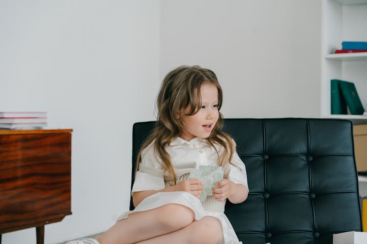 Photograph Of A Child Holding Cards