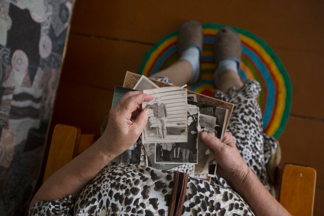 A pair of hands holding a small stack of old photographs.