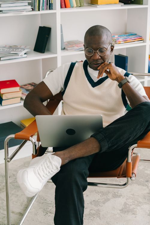 Free Bald man with glasses concentrates on laptop while seated in a stylish office setting. Stock Photo