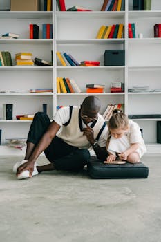 A dedicated tutor helps a young girl with her tablet in a library setting.
