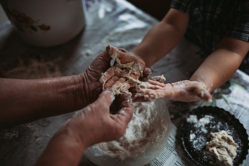 Free A touching moment of an elderly adult teaching a child how to make dough by hand in the kitchen. Stock Photo