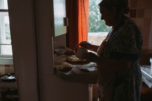 Free Silhouette of a woman preparing food in a cozy kitchen with soft natural lighting. Stock Photo