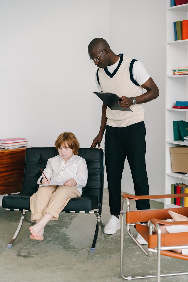 Man Watching Boy Filling In Document