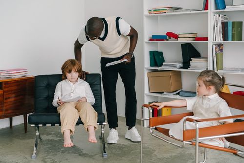 Free Therapist engaging with children in a modern office environment, focusing on child development. Stock Photo