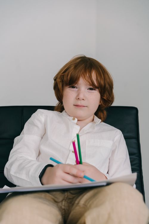 Free A focused child drawing with coloring pencils indoors, engaging in creative play. Stock Photo