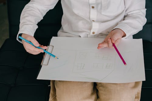 Close-Up Shot of a Child Drawing a House on a Paper