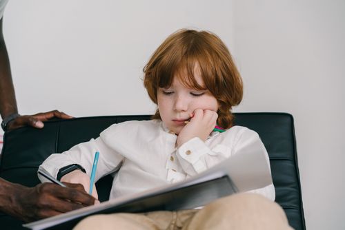 Free Young boy with freckles focused on drawing during an education session indoors. Stock Photo