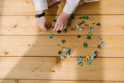 A child assembling colorful puzzle pieces on a sunlit wooden floor, capturing a moment of creativity and focus.