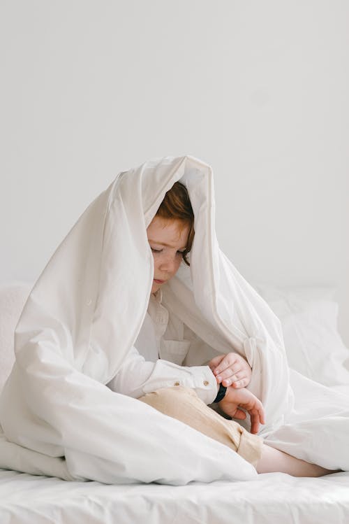 Free Child Sitting in Bed under Duvet Stock Photo