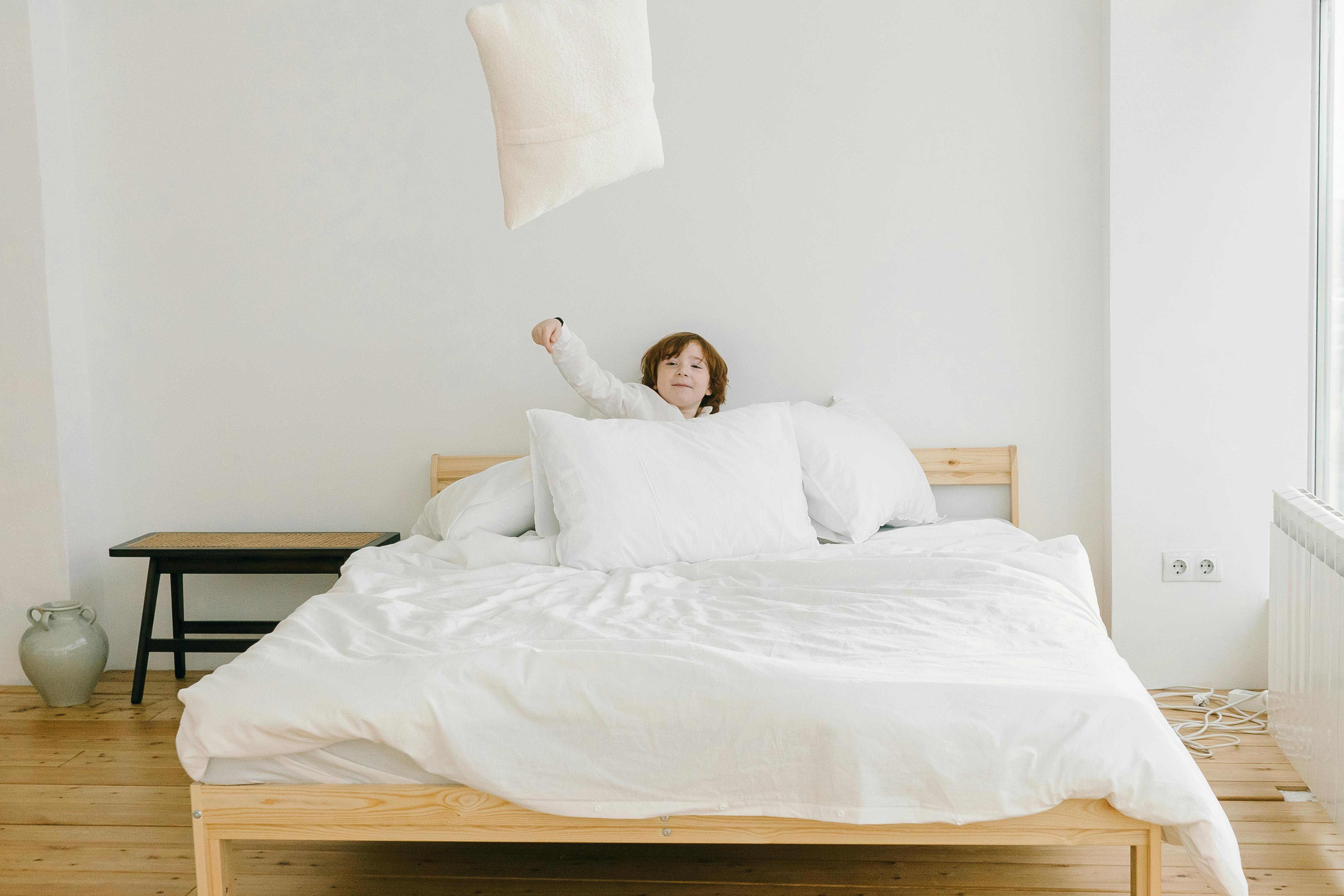 Child Throwing Pillows Out of the Bed · Free Stock Photo
