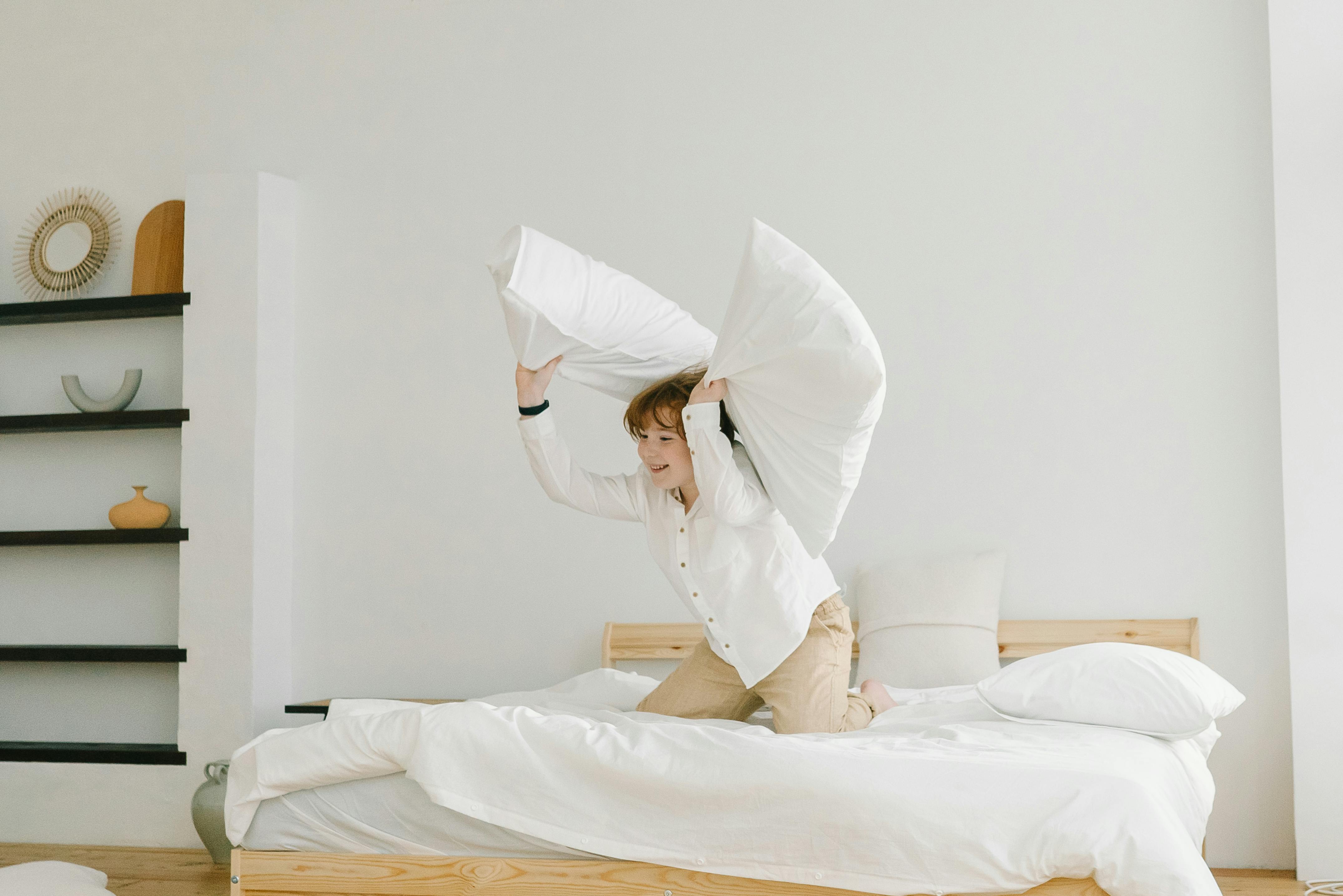 Child Throwing Pillows Out of the Bed · Free Stock Photo