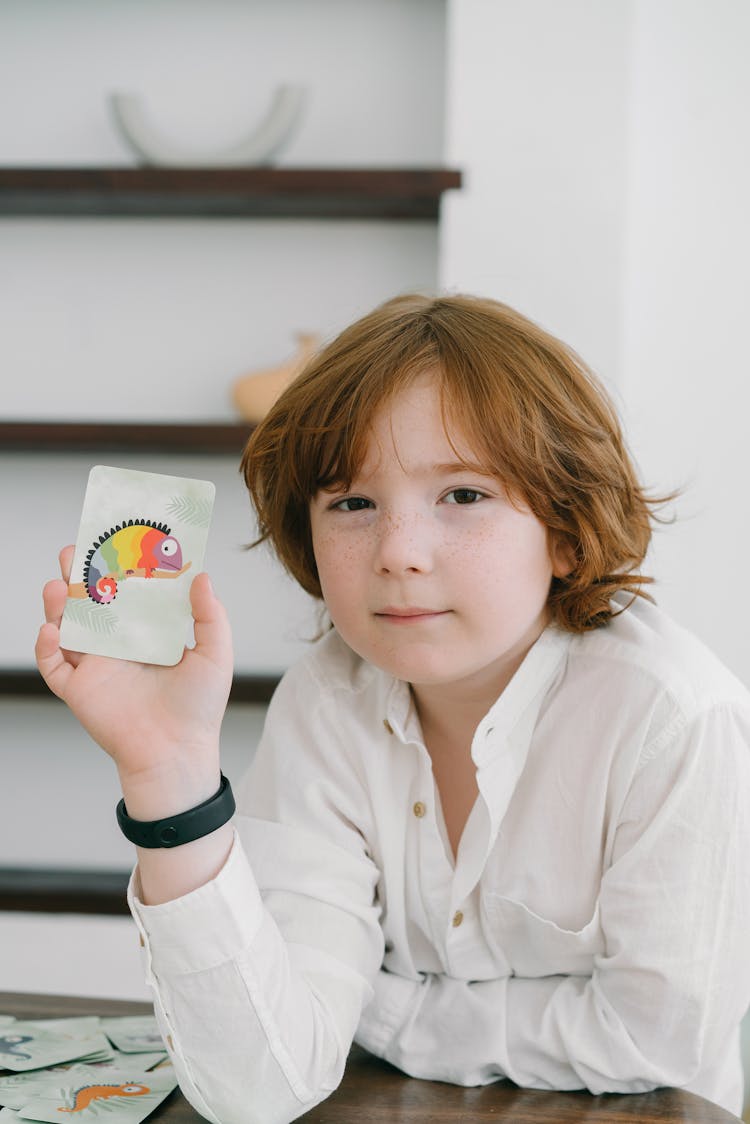 A Boy In White Long Sleeves Holding A Card