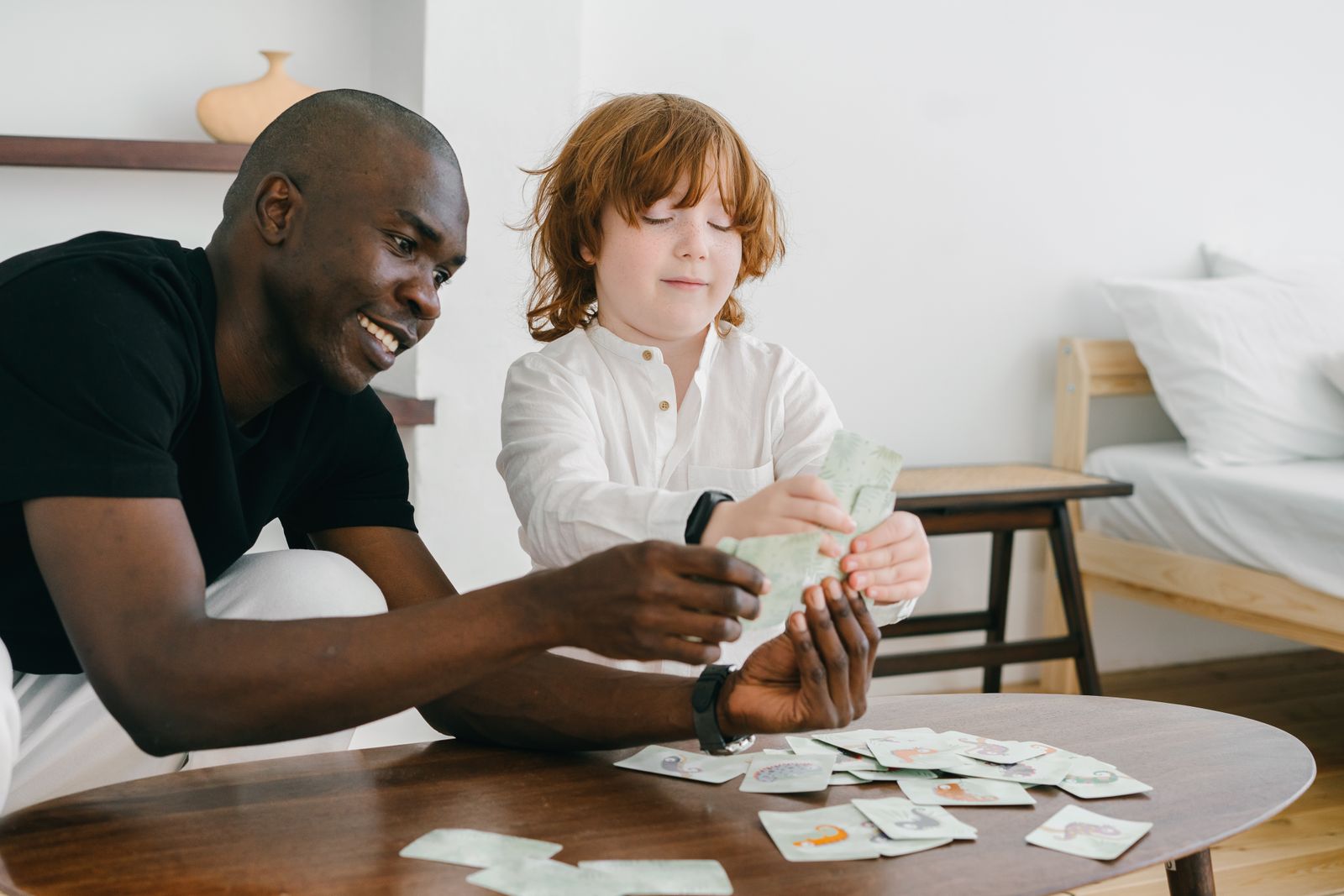A father and young child using cards together during a family learning game at a table