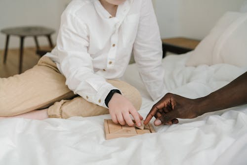 Unrecognizable Child and Person Playing with a Wooden Puzzle