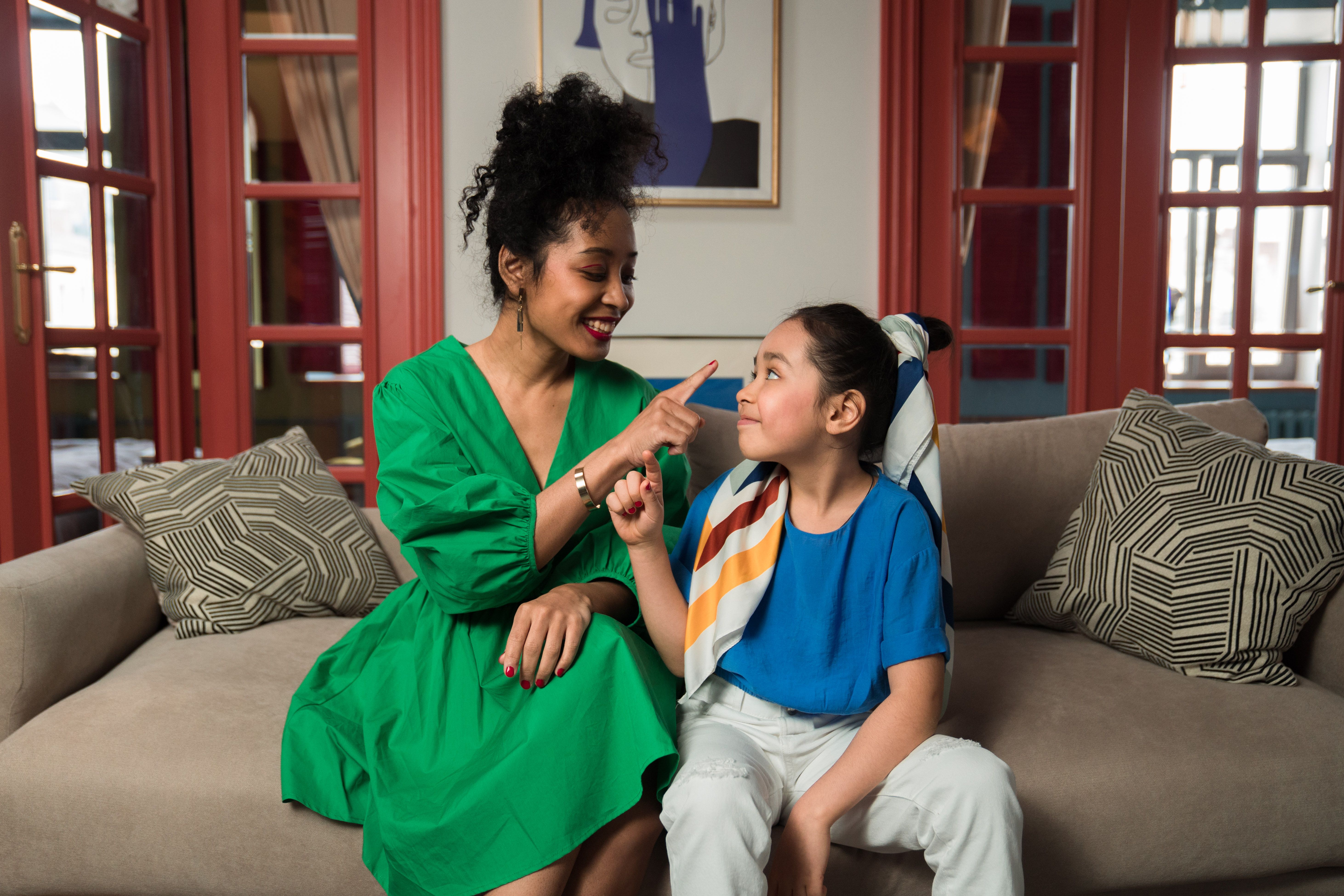 A mother and daughter share a joyful moment indoors, showcasing family bond and happiness.