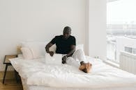 Man in Black Long Sleeve Shirt Lying on Bed