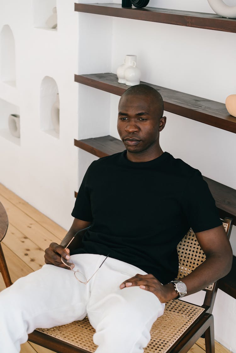 A Man Sitting On A Wooden Rattan Chair