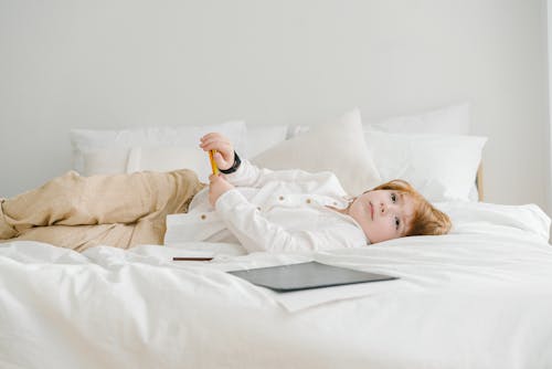 Boy Lying Down on a White Bed