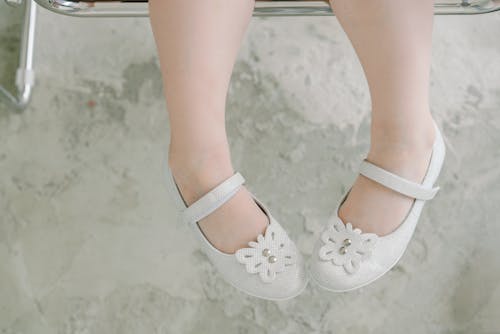 

A Close-Up Shot of a Child Wearing Doll Shoes