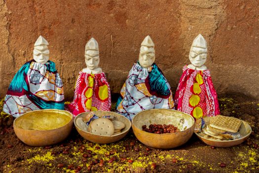 Colorful ceremonial figurines with ritual food bowls in Cotonou, Benin.