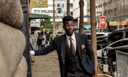 Free Well-dressed man in a suit posing on a busy urban street in Nairobi, Kenya. Stock Photo